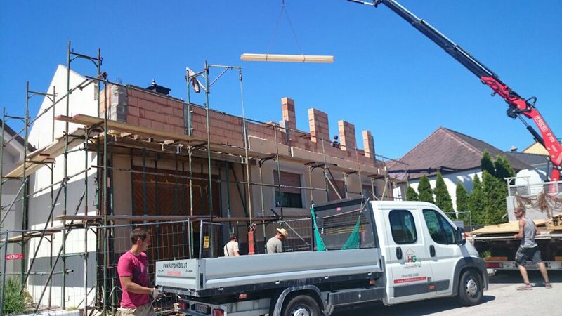 Firmenfahrzeuge und Mitarbeiter vor der Baustelle in Raiding